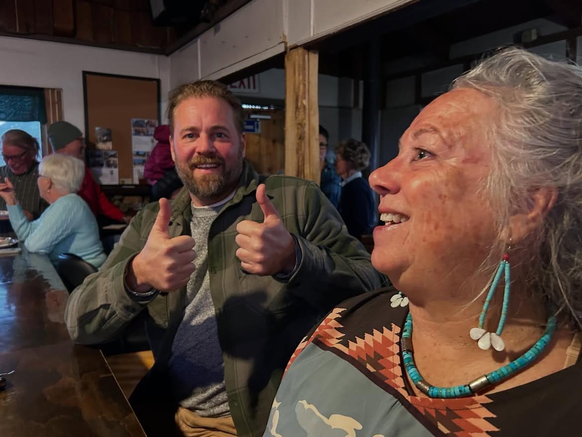 Two guests raising their thumbs to the camera in the dining room