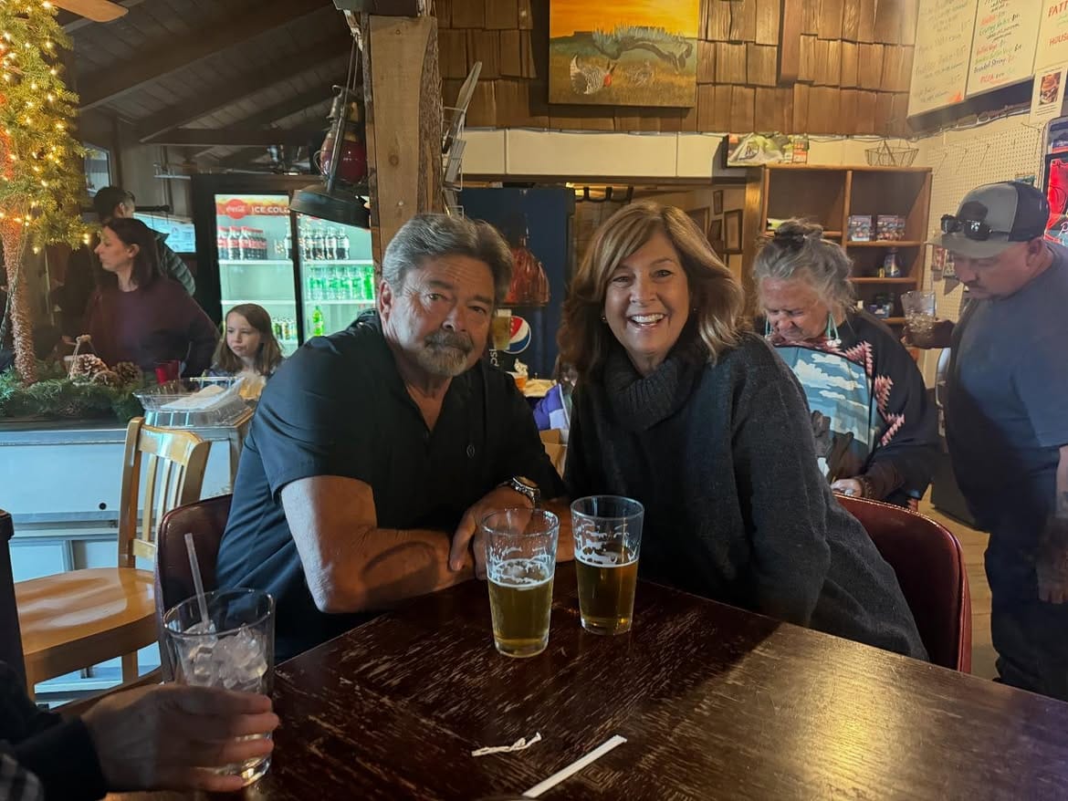 A couple at a table with glasses of beer between them